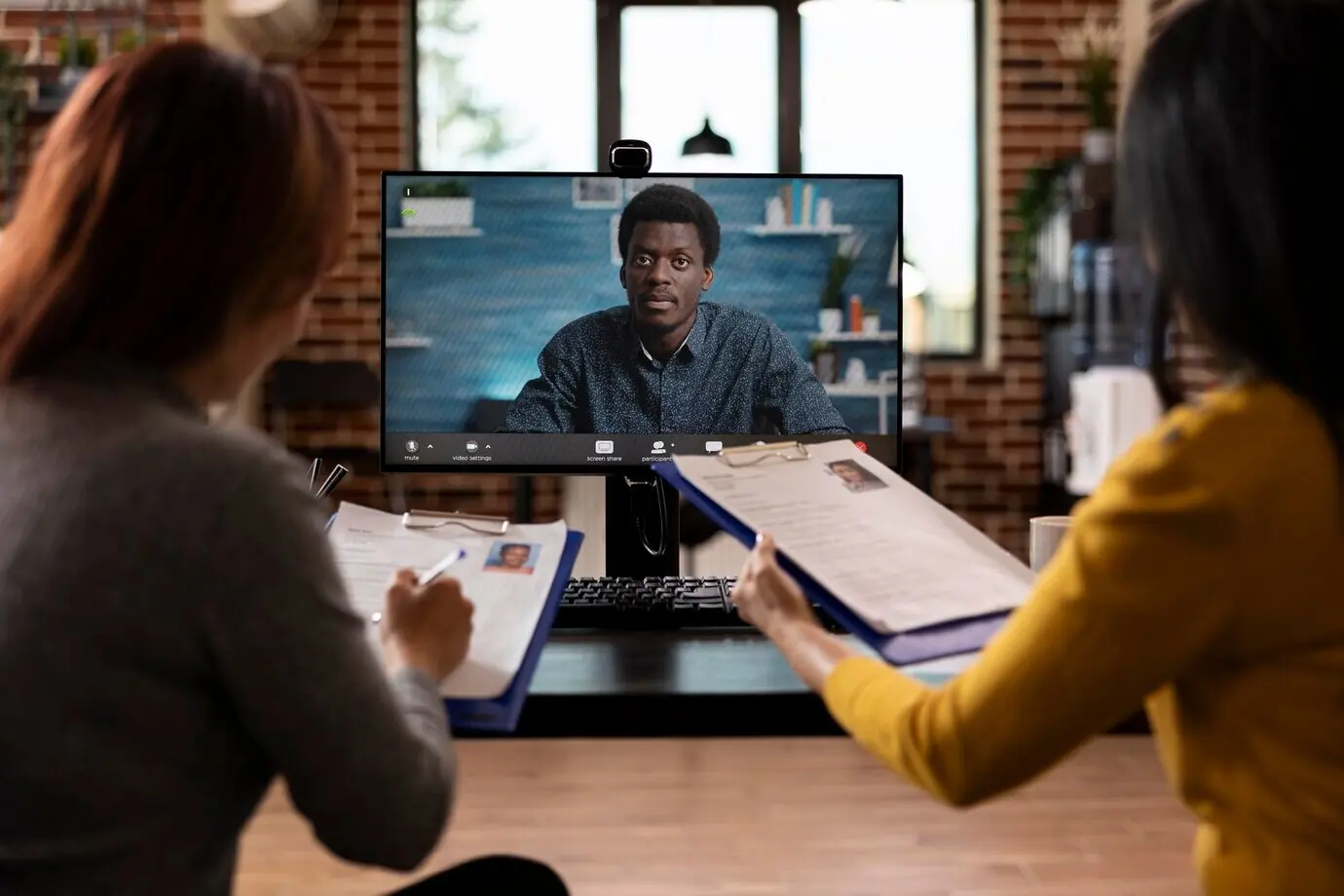 Команда отдела кадров проводит видеозвонок с чернокожим мужчиной.